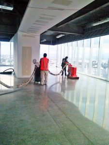 Workers polishing a concrete floor in a bright commercial interior